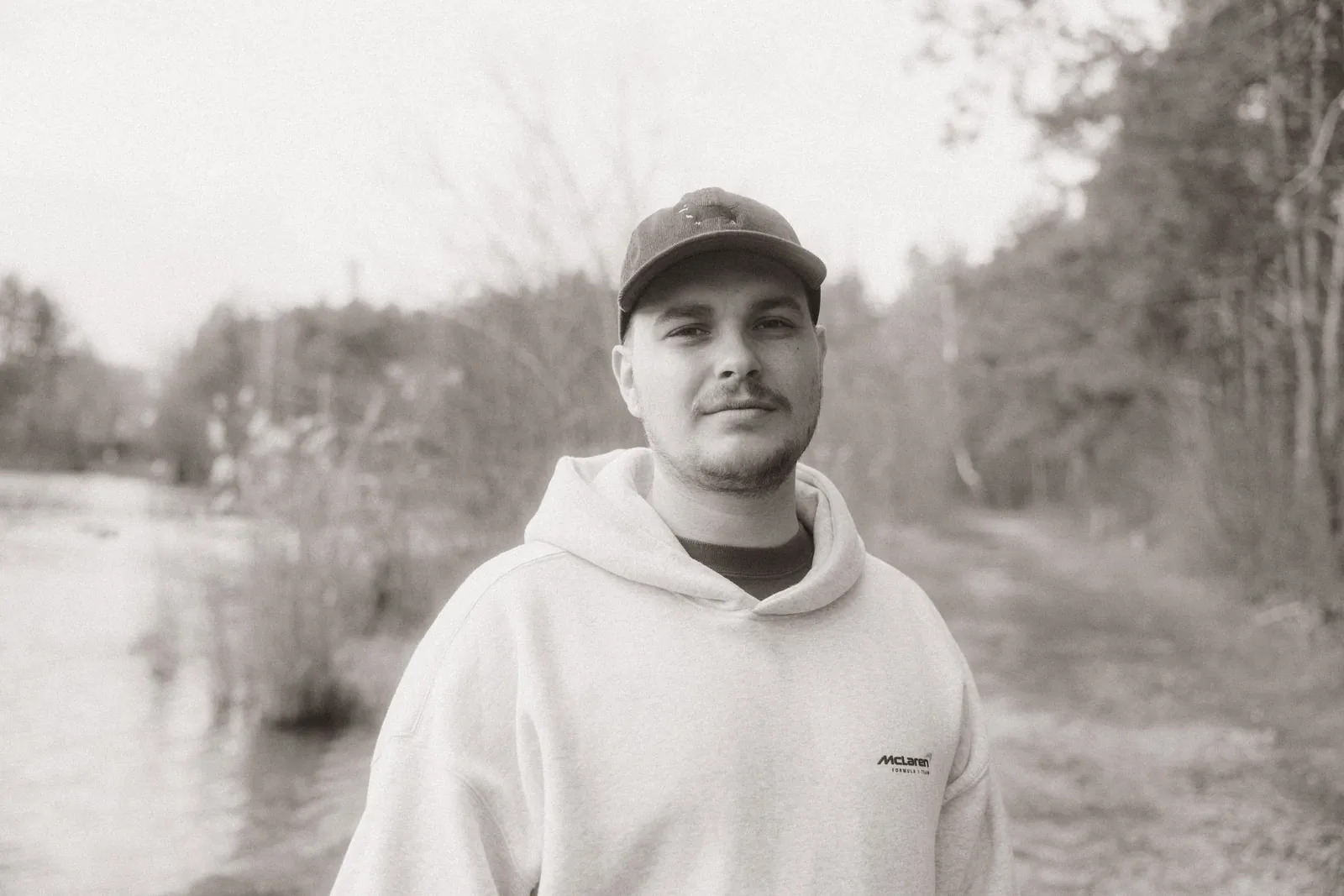 Black-and-white portrait of Dennis in a cap by a river
