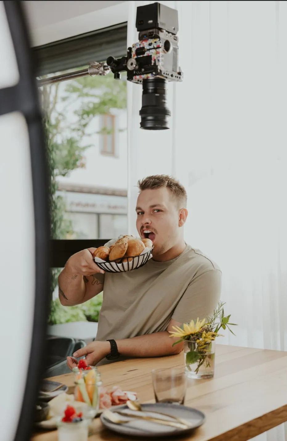 Dennis jokingly biting into a bread basket on set, the camera above him