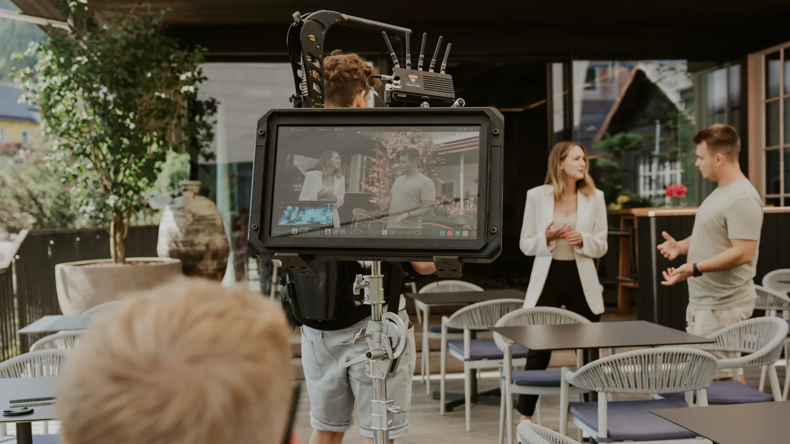 Shoot on a hotel terrace: field monitor in the foreground, Steadicam operator and two people in conversation